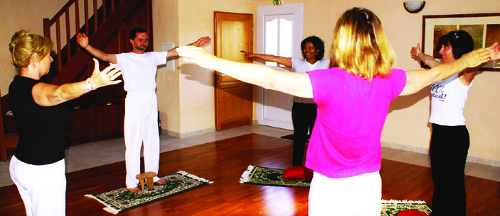 Cours collectif de Yoga de Samara, bras ouverts en posture debout